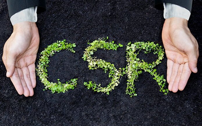 Hands of a businessman holding green plants arranged as a word "CSR" / Business ethics / Moral behavior in business / Corporate social responsibility