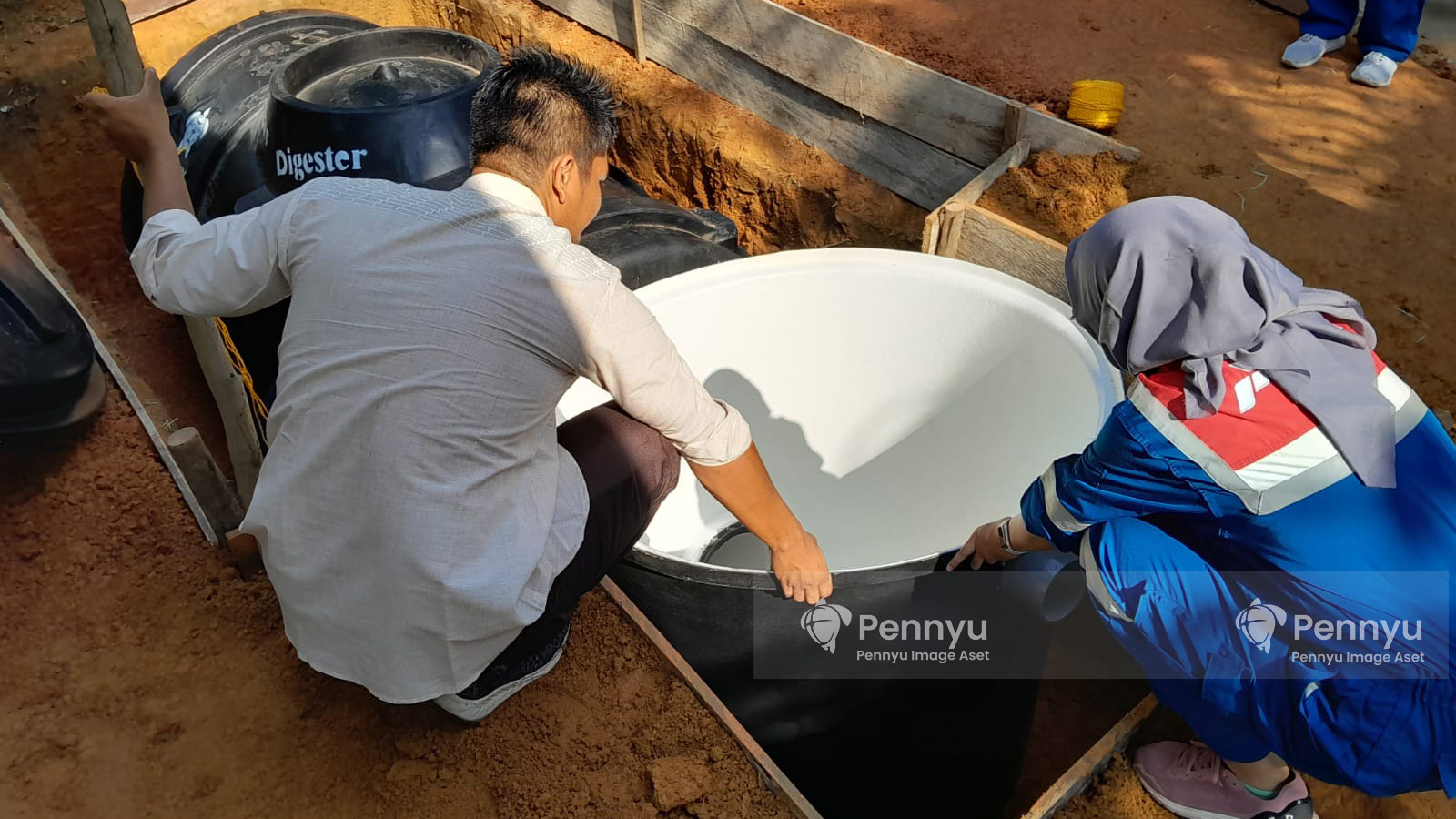 terdapat dua orang yang melakukan pengecekan instalasi Pennyu Biogas Digester