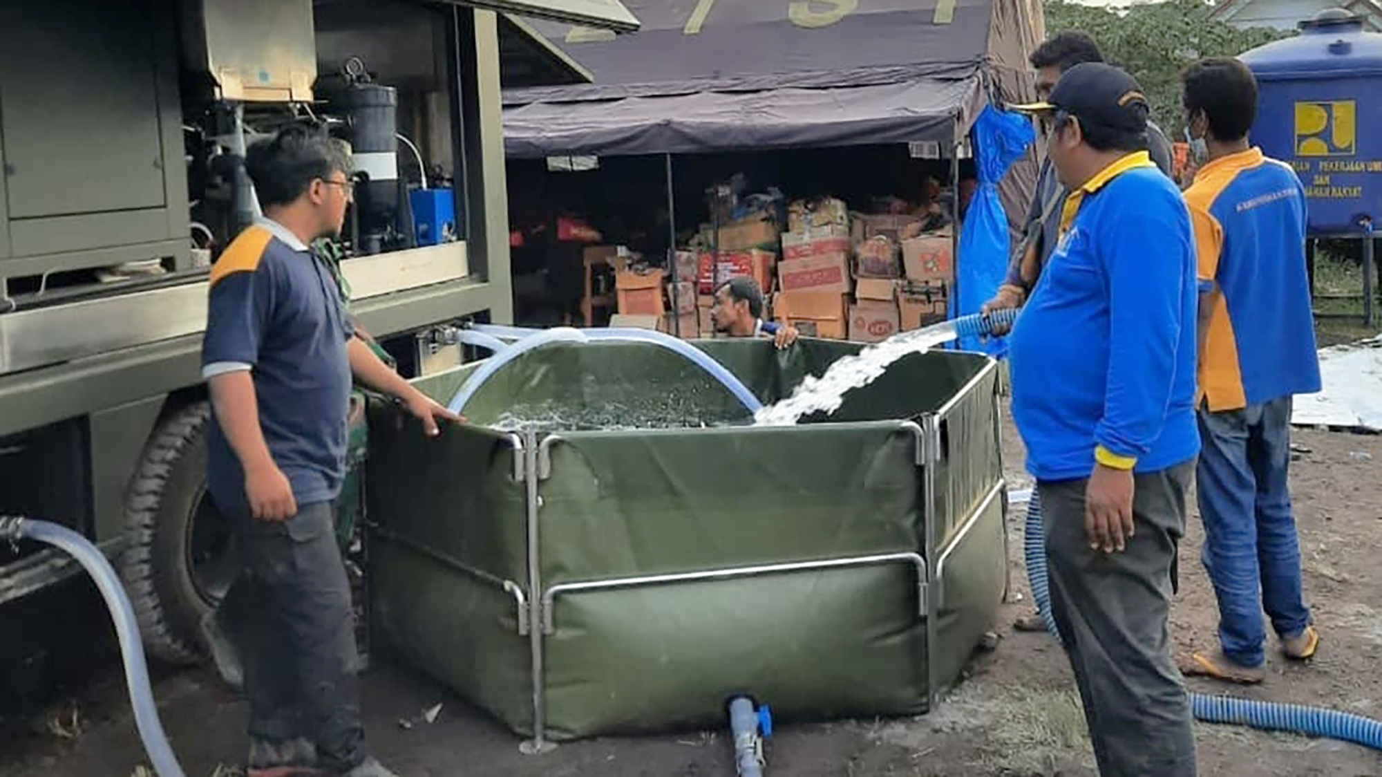 Beberapa orang yang sedang melakukan pengisian air bersih ke tandon air.